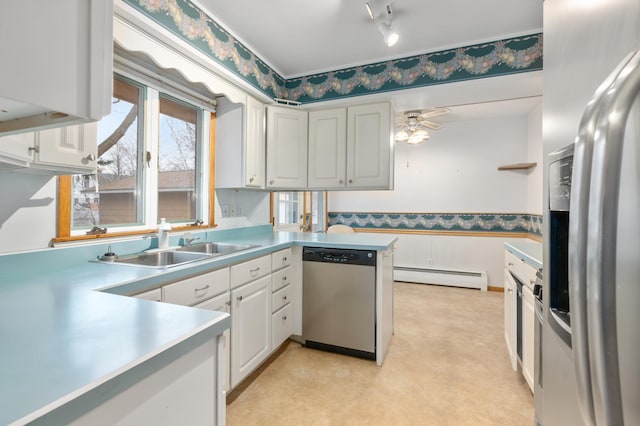 kitchen featuring appliances with stainless steel finishes, ceiling fan, sink, a baseboard radiator, and white cabinetry