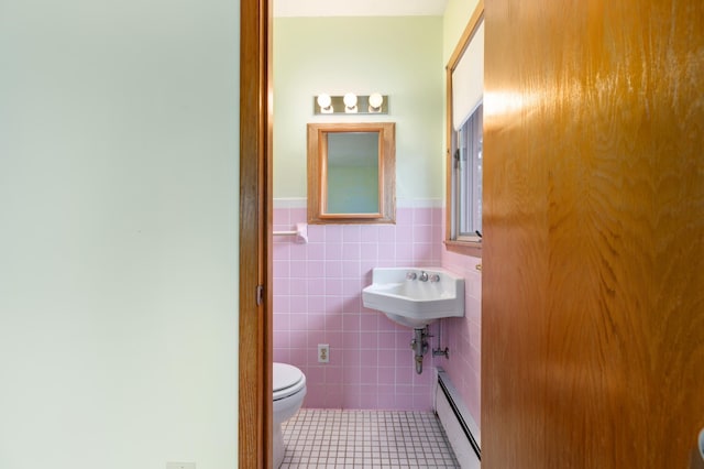 bathroom with toilet, tile patterned floors, tile walls, and a baseboard heating unit