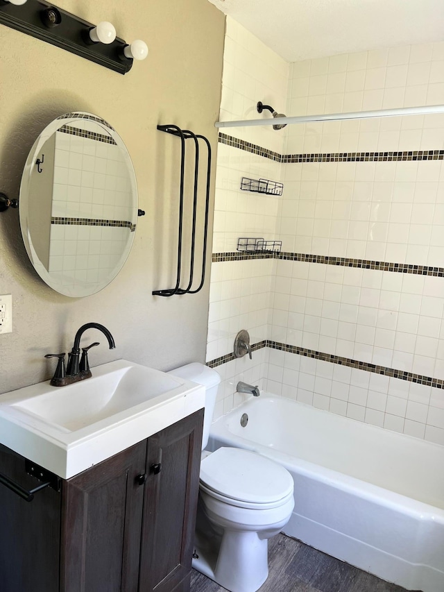 full bathroom with vanity, hardwood / wood-style flooring, toilet, and tiled shower / bath combo