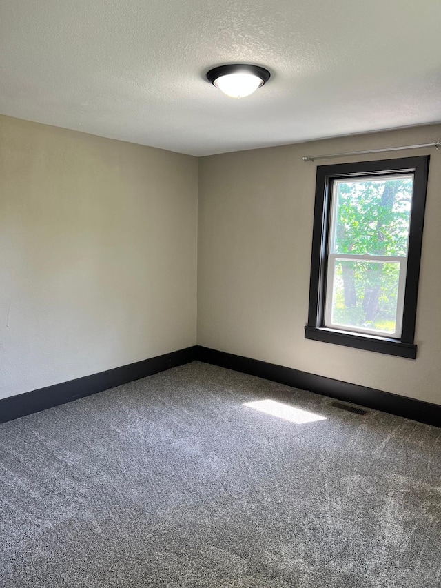 carpeted empty room with a textured ceiling