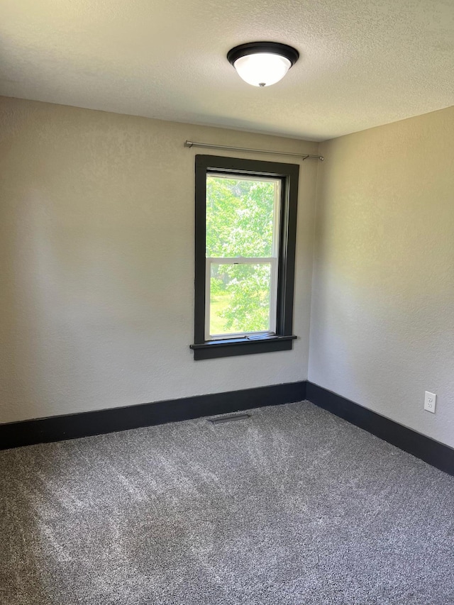 carpeted empty room with a textured ceiling