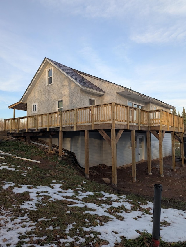 snow covered rear of property with a wooden deck