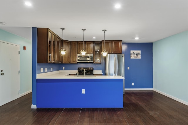 kitchen with appliances with stainless steel finishes, hanging light fixtures, dark wood-type flooring, and sink