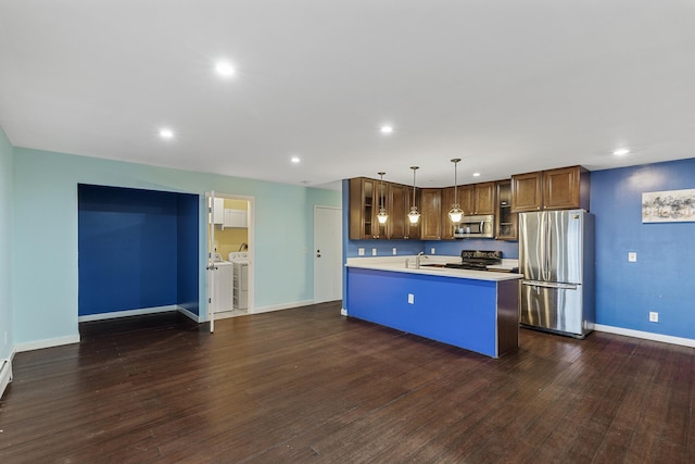 kitchen with stainless steel appliances, sink, pendant lighting, a center island with sink, and washing machine and clothes dryer