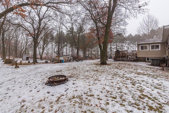 snowy yard featuring a deck, cooling unit, and a storage shed