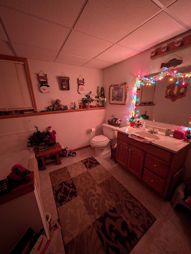 bathroom with vanity, toilet, tile patterned flooring, and a drop ceiling