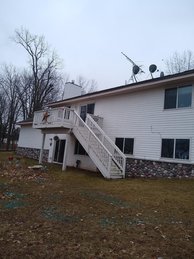 back of house featuring a wooden deck, stairway, a yard, and a chimney