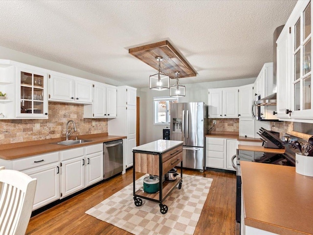 kitchen featuring sink, hanging light fixtures, decorative backsplash, white cabinetry, and stainless steel appliances