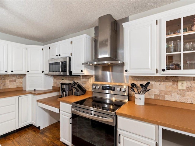 kitchen featuring wall chimney exhaust hood, a textured ceiling, decorative backsplash, white cabinets, and appliances with stainless steel finishes