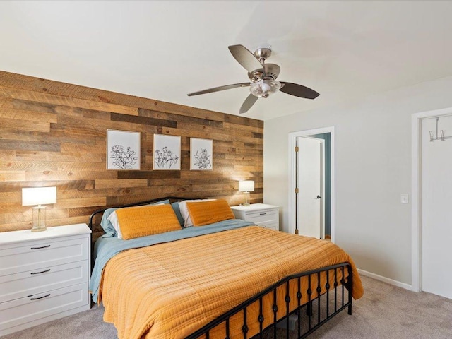 carpeted bedroom featuring wood walls and ceiling fan