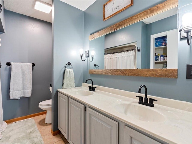 bathroom with tile patterned flooring, vanity, and toilet