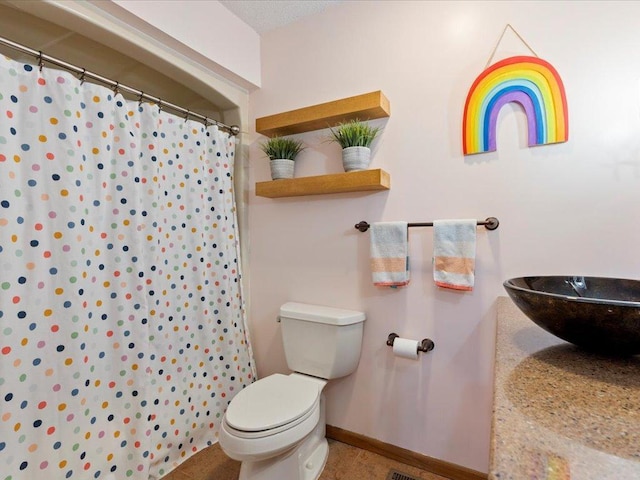 bathroom featuring tile patterned flooring, toilet, walk in shower, and sink