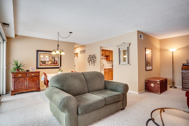 carpeted living room featuring a textured ceiling and a notable chandelier