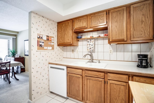 kitchen with sink, light tile patterned floors, dishwasher, backsplash, and a textured ceiling