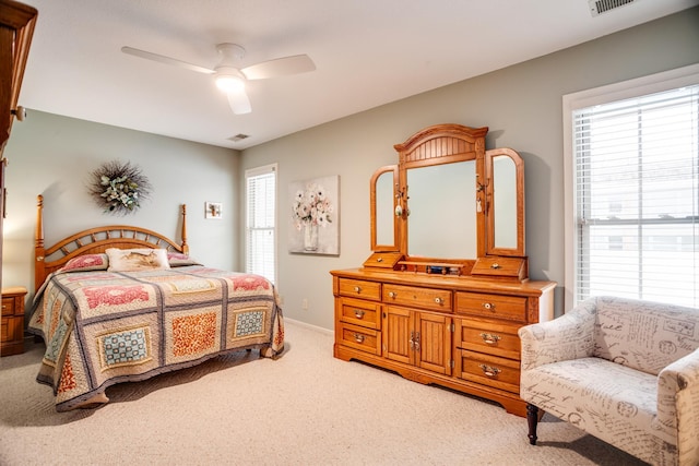 bedroom featuring multiple windows, light carpet, and ceiling fan