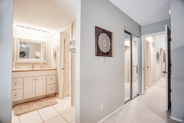 hallway featuring sink and light tile patterned flooring