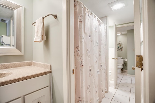 bathroom with tile patterned flooring, vanity, and toilet