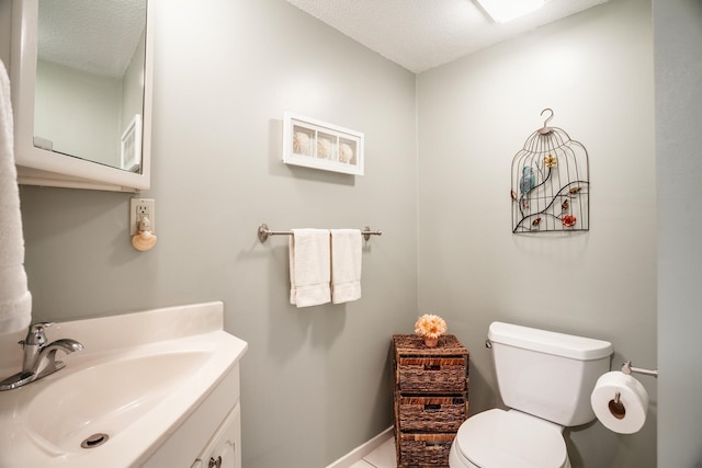 bathroom with tile patterned flooring, vanity, a textured ceiling, and toilet