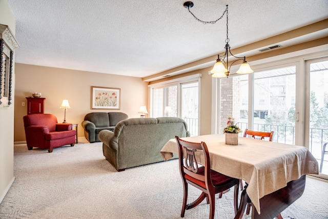 dining room featuring light carpet, a chandelier, and a textured ceiling