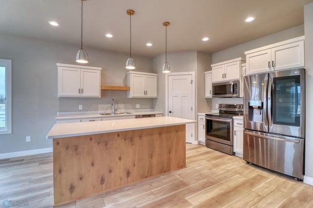 kitchen featuring white cabinets, a center island, stainless steel appliances, and hanging light fixtures