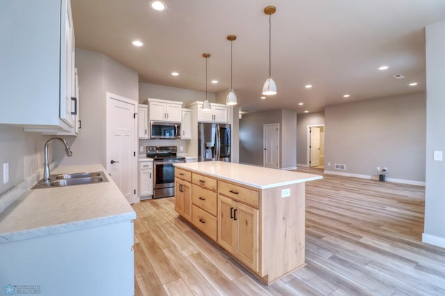 kitchen with stainless steel appliances, sink, decorative light fixtures, white cabinetry, and a kitchen island