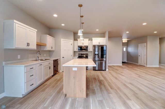 kitchen featuring sink, a center island, hanging light fixtures, white cabinets, and appliances with stainless steel finishes