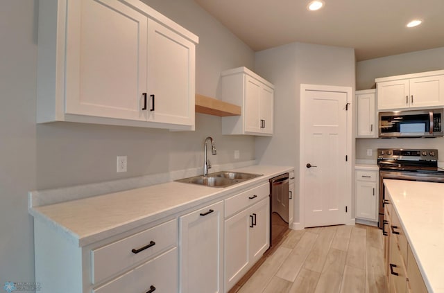 kitchen featuring white cabinets, appliances with stainless steel finishes, light wood-type flooring, and sink