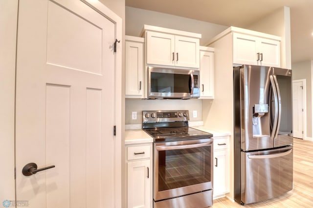 kitchen with light hardwood / wood-style floors, white cabinetry, and appliances with stainless steel finishes