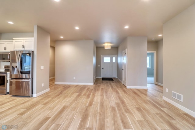 kitchen with stainless steel appliances, white cabinetry, and light hardwood / wood-style flooring