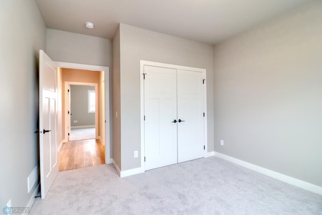 unfurnished bedroom featuring light carpet and a closet