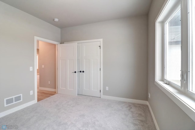 unfurnished bedroom featuring light carpet and a closet