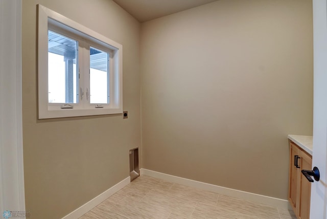 washroom with electric dryer hookup and cabinets