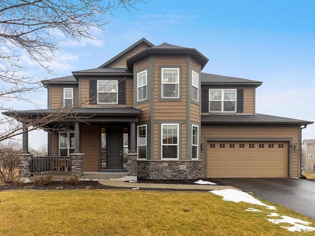 view of front of property with covered porch, a garage, and a front lawn