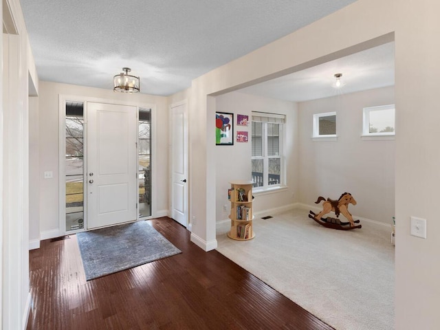 entryway featuring a textured ceiling, a wealth of natural light, and dark hardwood / wood-style floors