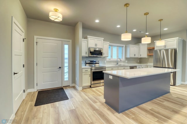 kitchen with white cabinets, a center island, stainless steel appliances, and hanging light fixtures