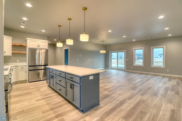 kitchen with pendant lighting, light hardwood / wood-style flooring, gray cabinets, white cabinetry, and stainless steel refrigerator