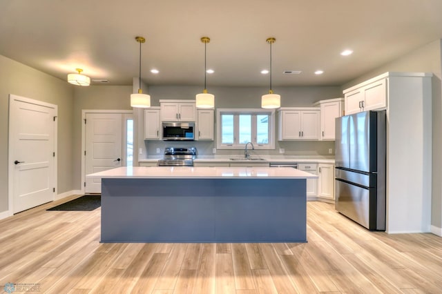 kitchen with a center island, sink, white cabinets, and stainless steel appliances