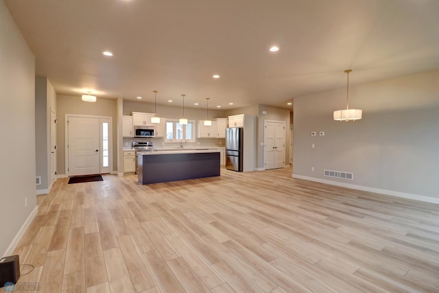 kitchen featuring white cabinets, a kitchen island, stainless steel appliances, and hanging light fixtures