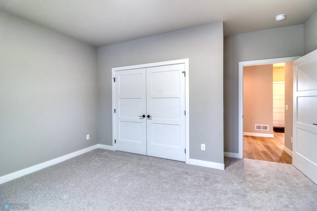 unfurnished bedroom featuring light carpet and a closet