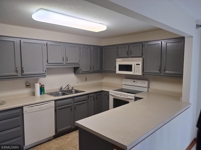 kitchen with kitchen peninsula, a textured ceiling, white appliances, sink, and gray cabinets