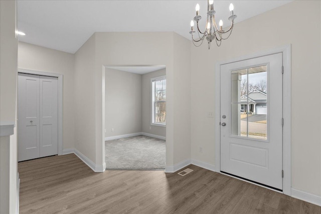 entryway featuring light wood finished floors, baseboards, a chandelier, and visible vents