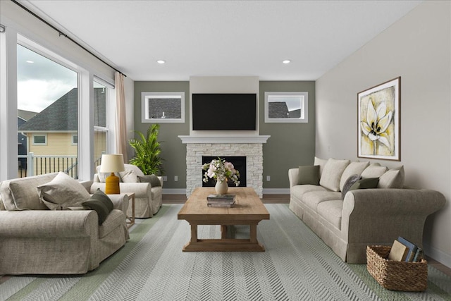living room featuring baseboards, a stone fireplace, wood finished floors, and recessed lighting