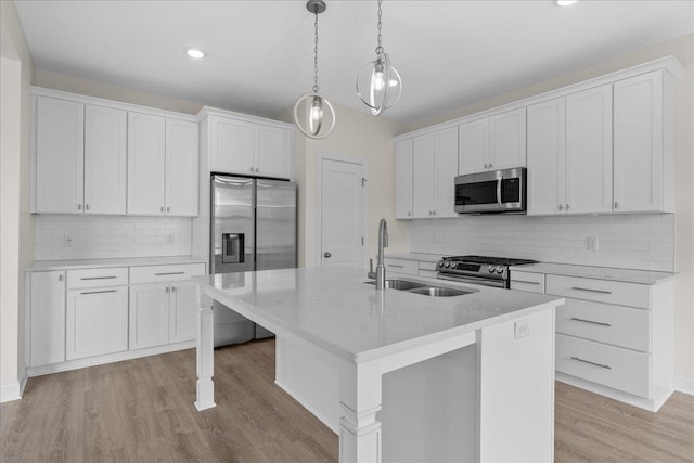 kitchen with an island with sink, a sink, decorative backsplash, appliances with stainless steel finishes, and white cabinetry
