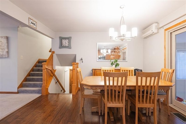 dining area with dark wood-type flooring, a wall unit AC, and a notable chandelier