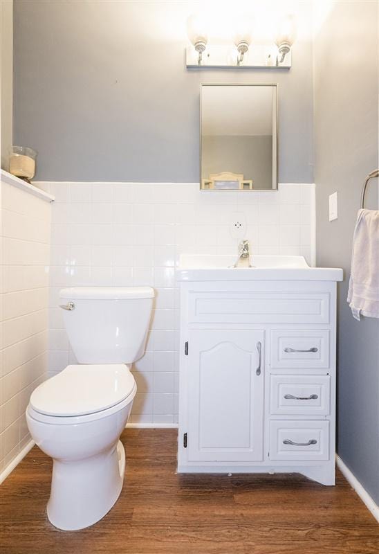 bathroom with hardwood / wood-style flooring, vanity, toilet, and tile walls