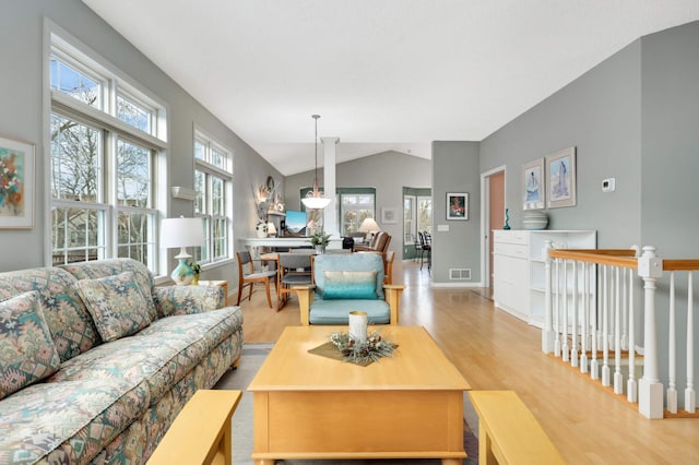 living room featuring lofted ceiling and light hardwood / wood-style floors