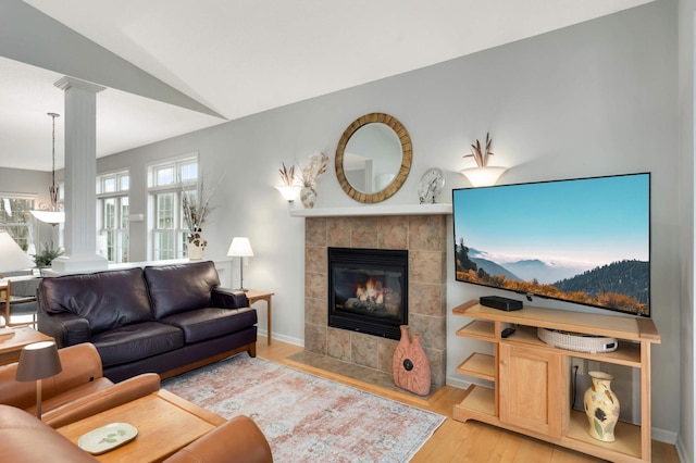 living room with hardwood / wood-style flooring, vaulted ceiling, a fireplace, and ornate columns