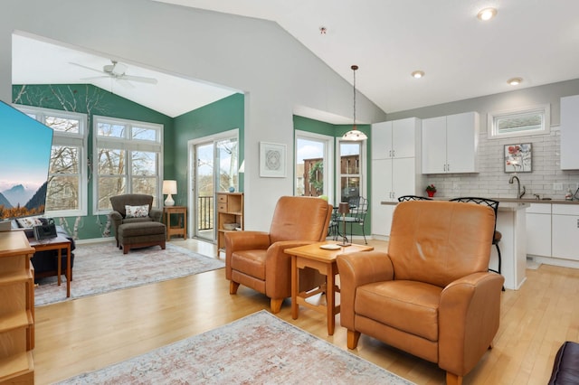 living room featuring ceiling fan, vaulted ceiling, and light hardwood / wood-style flooring