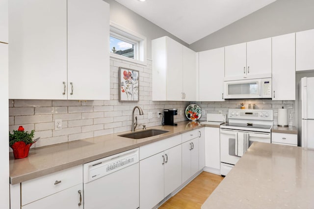 kitchen with vaulted ceiling, white cabinetry, sink, decorative backsplash, and white appliances