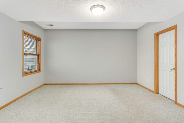 carpeted empty room with a textured ceiling